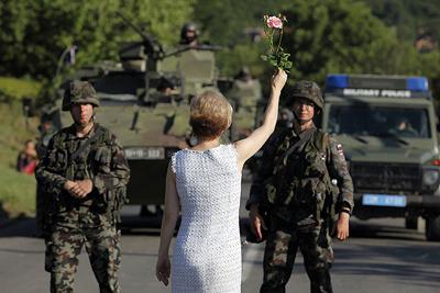 A Kosovo Serb woman holds a flower in front of Slovenia's KFOR soldiers in Rudare near  Zvecan